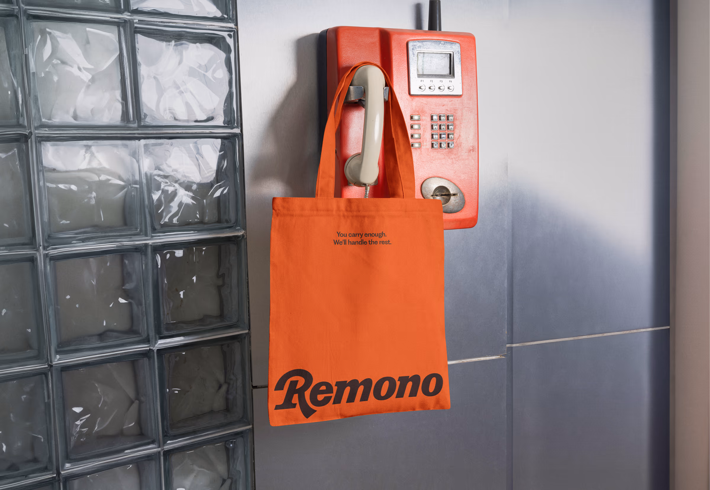 Orange Remono tote bag hanging from a red payphone