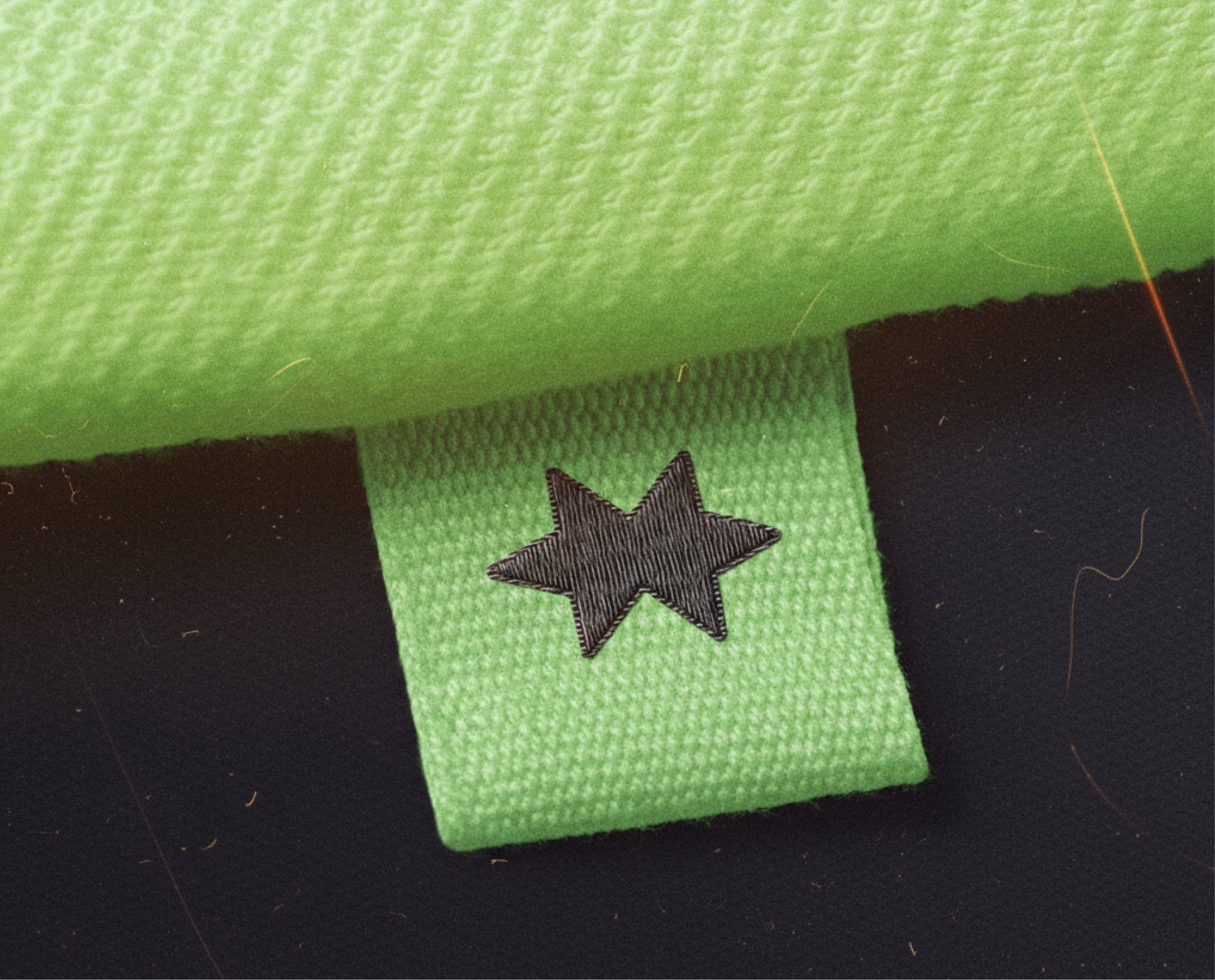 Green woven garment label with a stitched black Smeash star