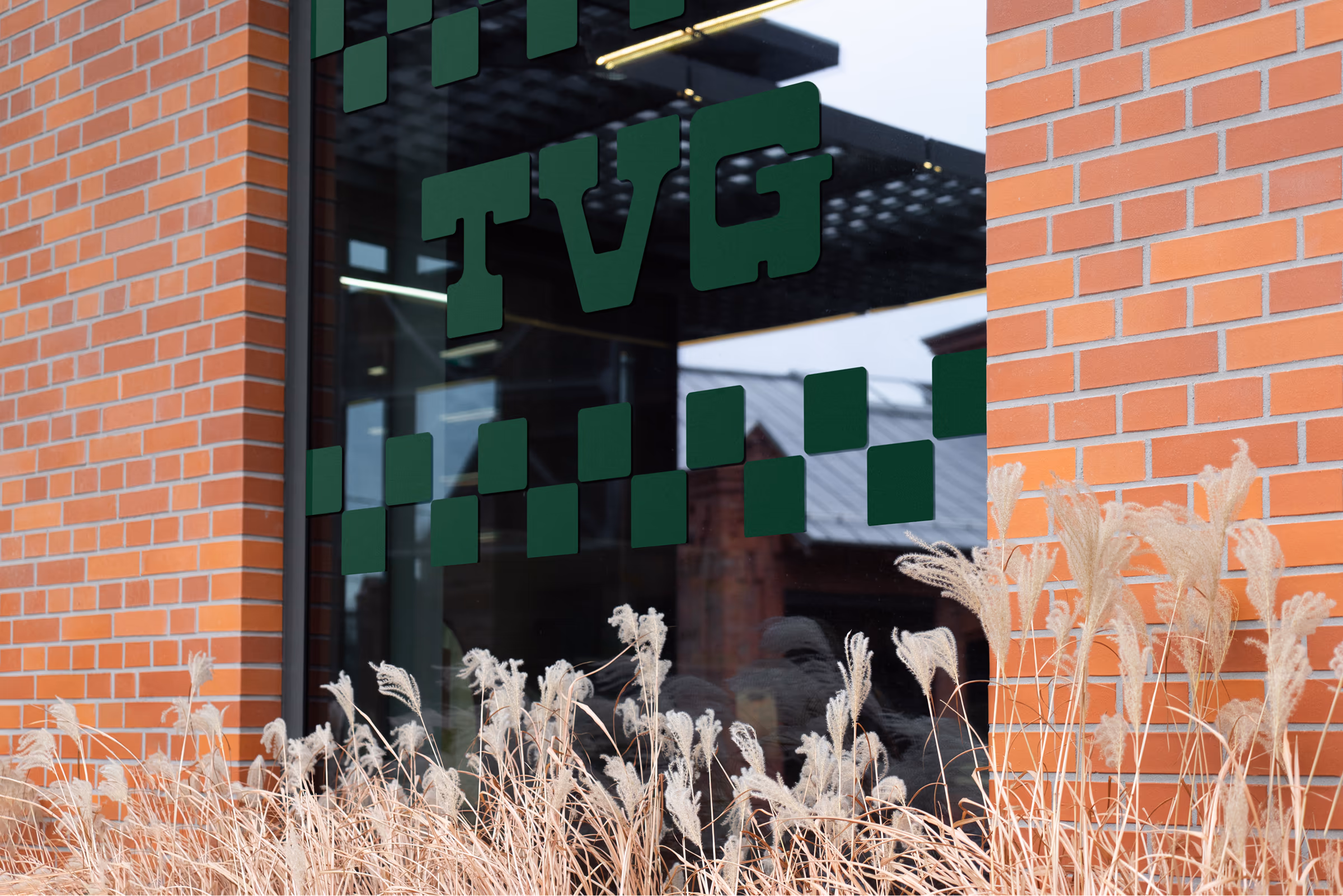 TVG window vinyl on a brick storefront, dark green wordmark and checkered pattern on glass