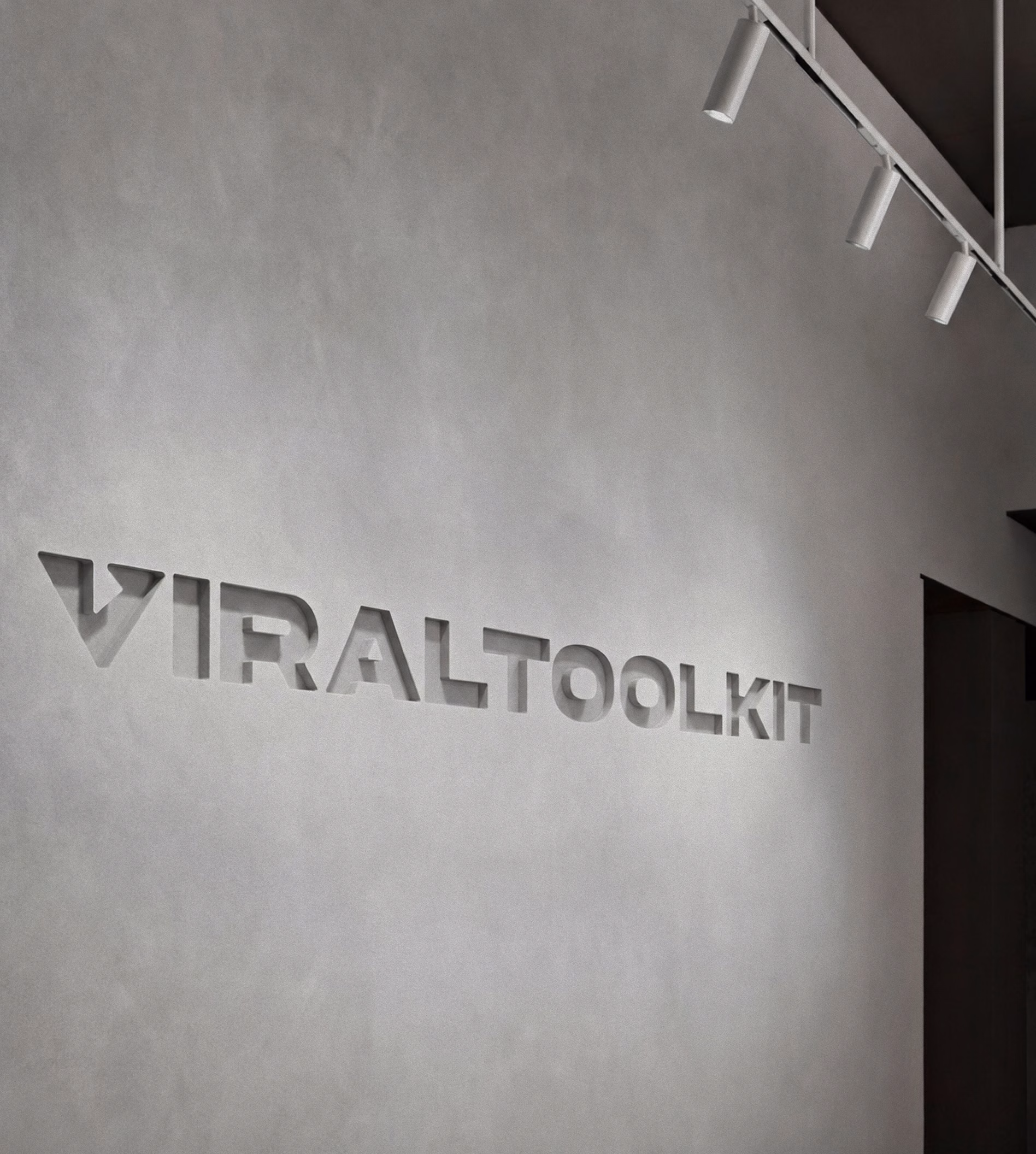 Viral Toolkit wordmark debossed into a concrete office wall