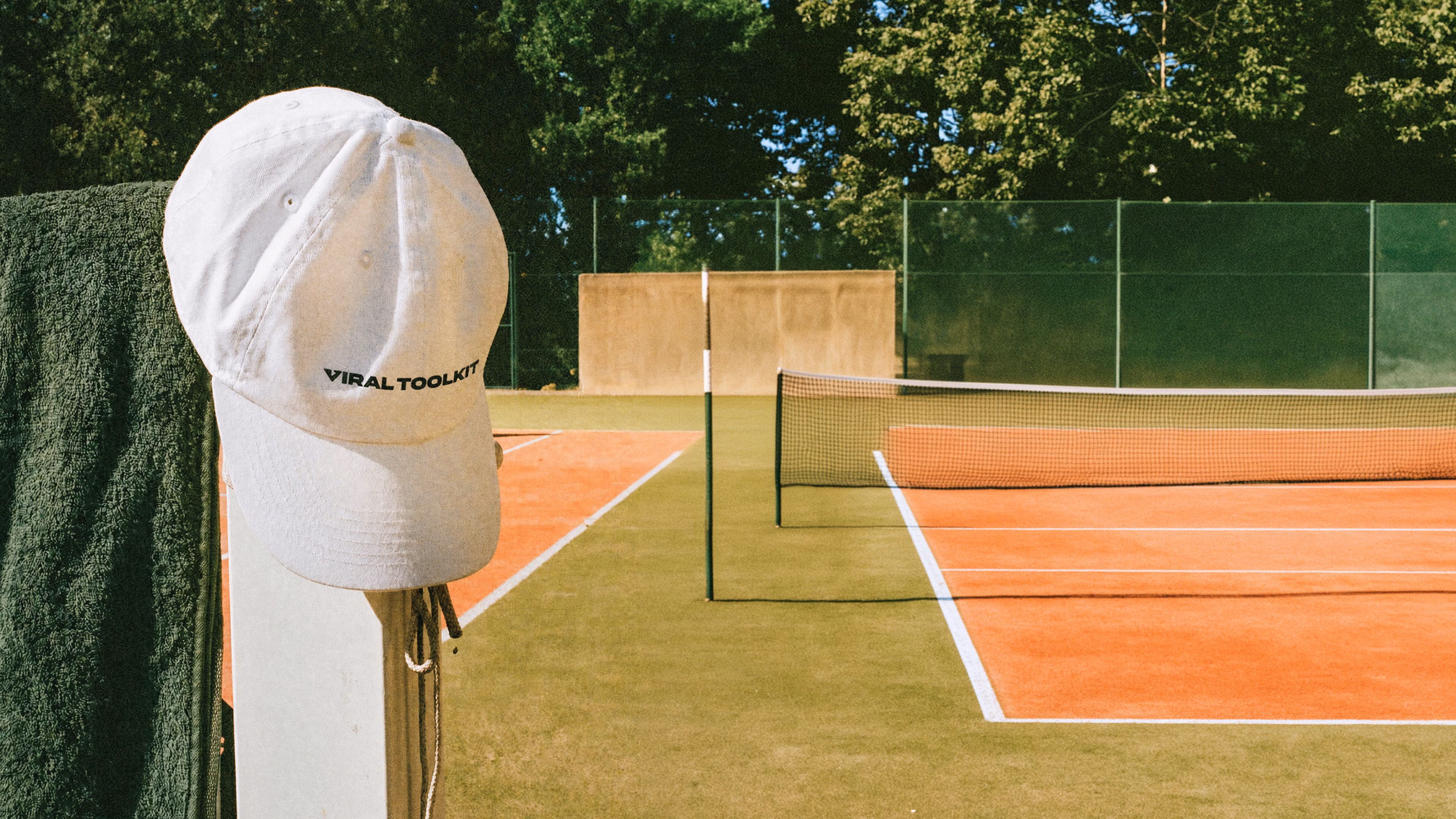 White Viral Toolkit cap hanging courtside at a clay tennis court