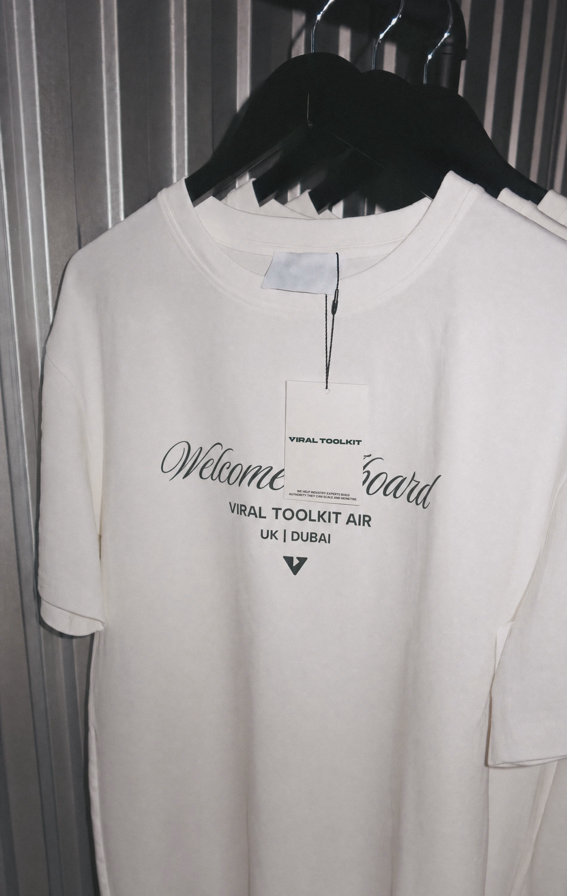 White Viral Toolkit Air tee on a rail, reading Welcome aboard, UK to Dubai